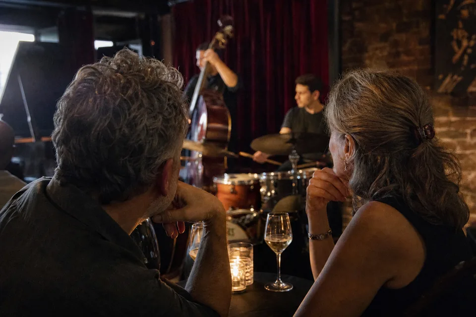 A couple in their mid fifties listening to live music at a small New York jazz club