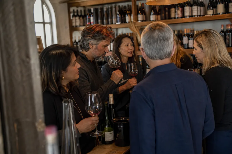 A small group of adults in their forties to sixties chatting at a wine tasting